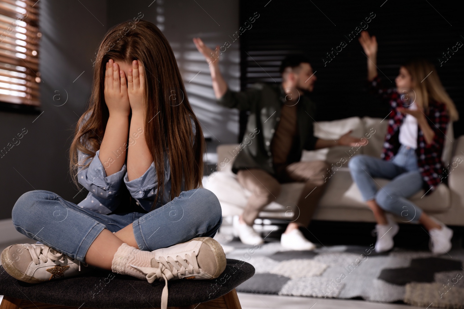 Photo of Couple fighting at home, focus on their unhappy little daughter. Domestic violence