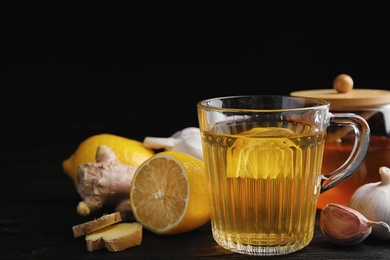 Photo of Composition with cold remedies on black wooden table. Sore throat treatment