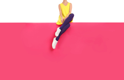 Woman wearing purple tights and stylish shoes sitting on color background, closeup