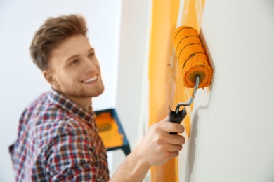 Photo of Happy young man painting wall indoors. Home repair