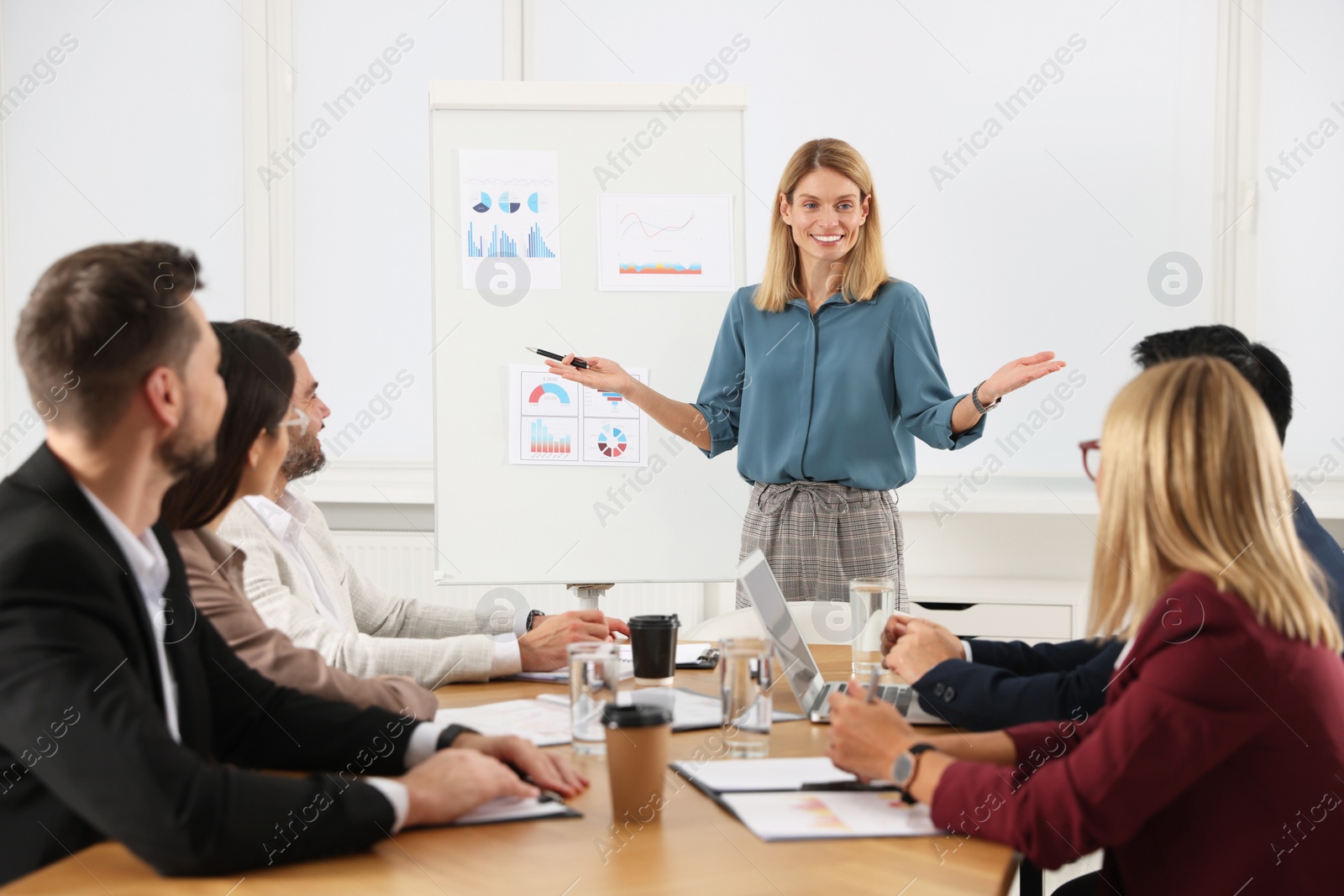 Photo of Businesswoman showing charts near flipchart on meeting in office