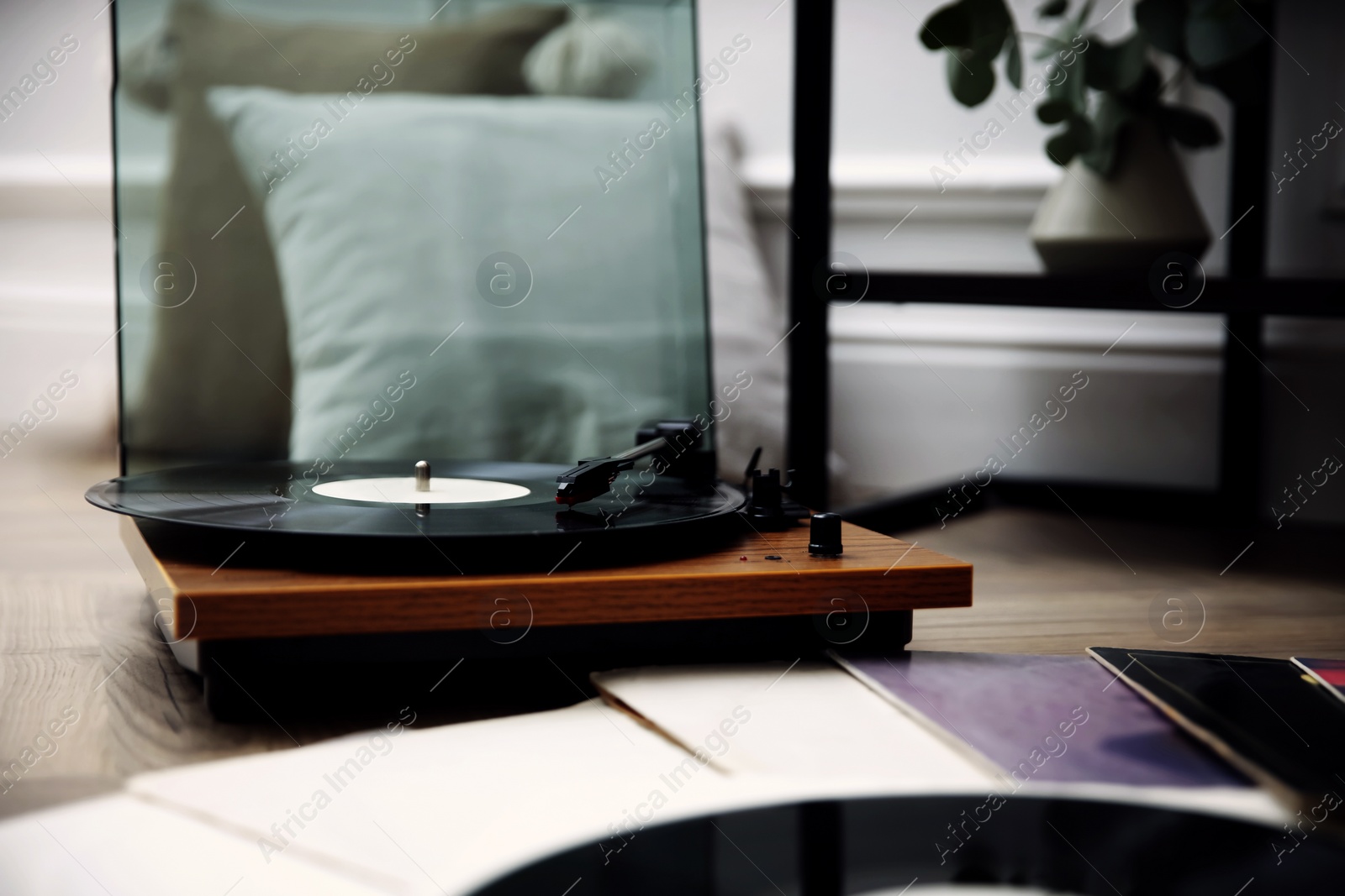 Image of Stylish turntable with vinyl records on floor indoors