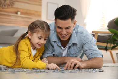 Photo of Happy father and his daughter playing with puzzles on floor at home