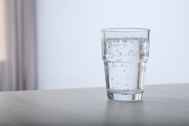 Photo of Glass of water on table against blurred background. Space for text