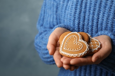 Woman with tasty heart shaped gingerbread cookies on blue background, closeup