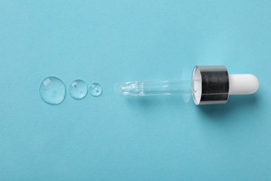Photo of Clear cosmetic serum and pipette on light blue background, top view