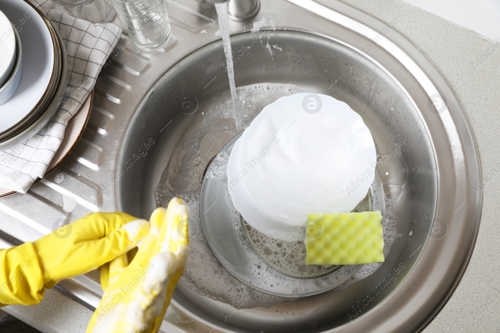 Photo of Woman washing plates near kitchen sink, above view