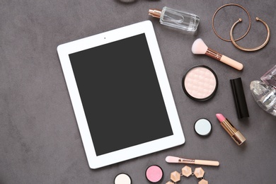 Photo of Flat lay composition with tablet and makeup products for woman on grey background