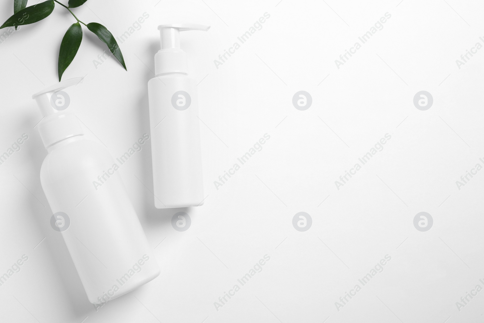 Photo of Bottles with different cosmetic products and green leaves on white background, flat lay. Space for text