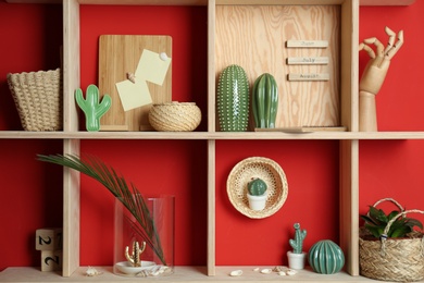 Photo of Stylish wooden shelves with decorative elements on red wall