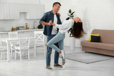 Happy couple dancing in kitchen at home