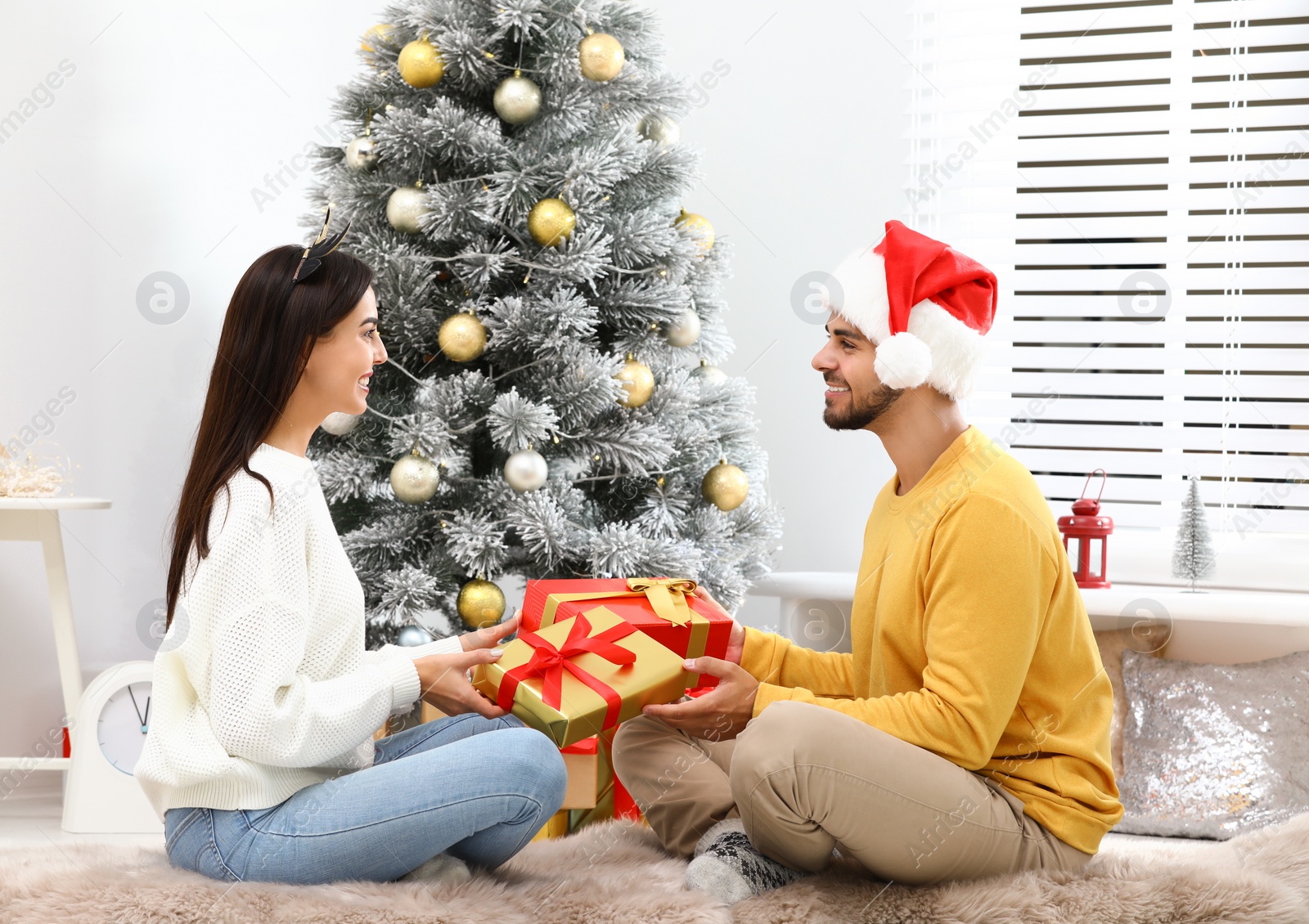 Photo of Happy young couple exchanging Christmas gifts at home