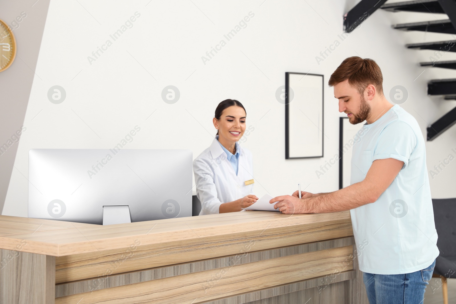 Photo of Professional receptionist working with patient at desk in modern clinic