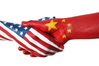 Photo of USA and China partnership. People shaking hands painted in flags on white background, closeup