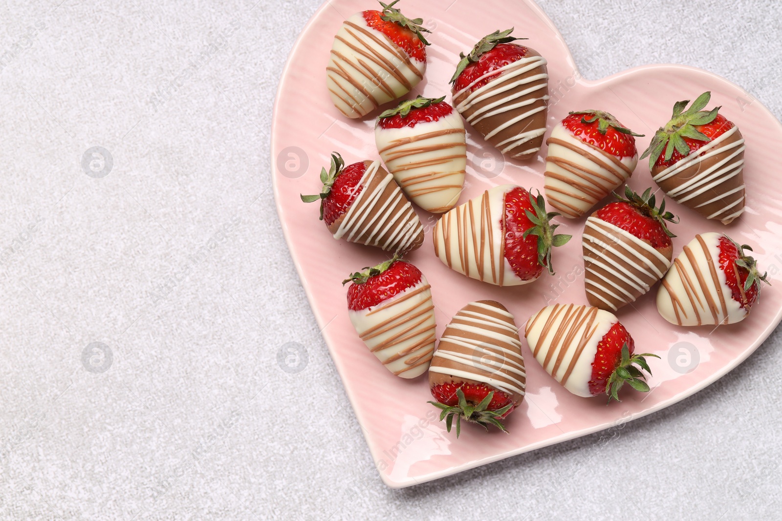 Photo of Heart shaped plate with delicious chocolate covered strawberries on light table, top view. Space for text