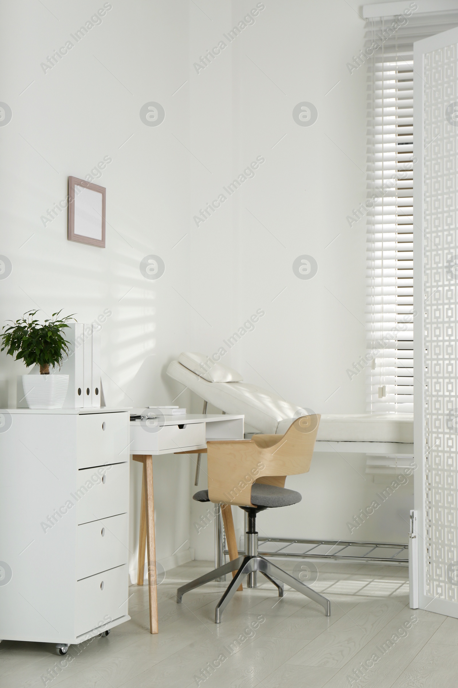 Photo of Examination room with modern couch and folding screen in clinic. Medical office interior