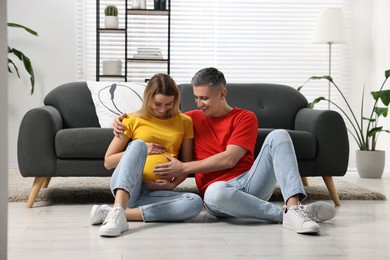 Young family housing concept. Pregnant woman with her husband on floor at home