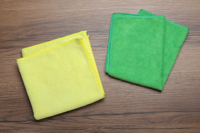 Green and yellow microfiber cloths on wooden table, flat lay