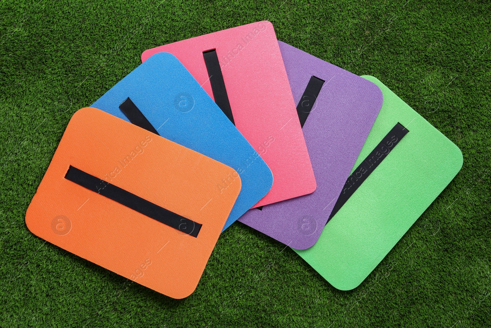 Photo of Bright foam tourist seat mats on green grass, flat lay