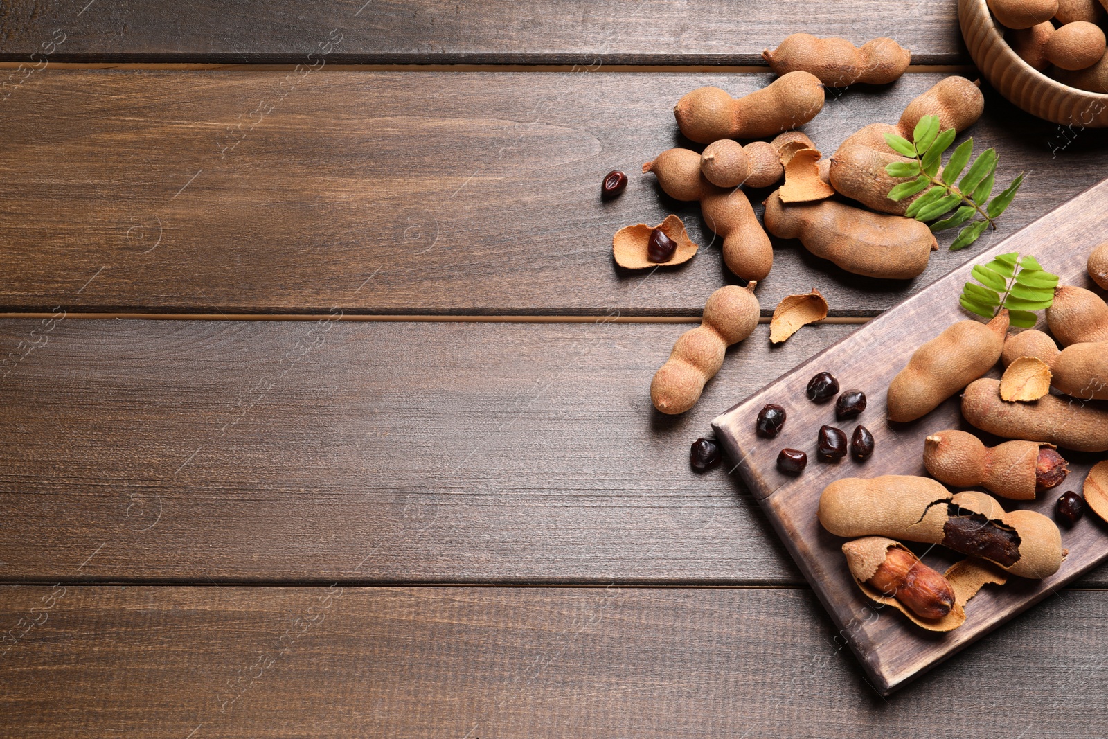 Photo of Delicious ripe tamarinds on wooden table, flat lay. Space for text