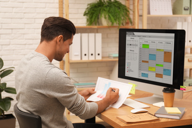 Man working with calendar at table in office