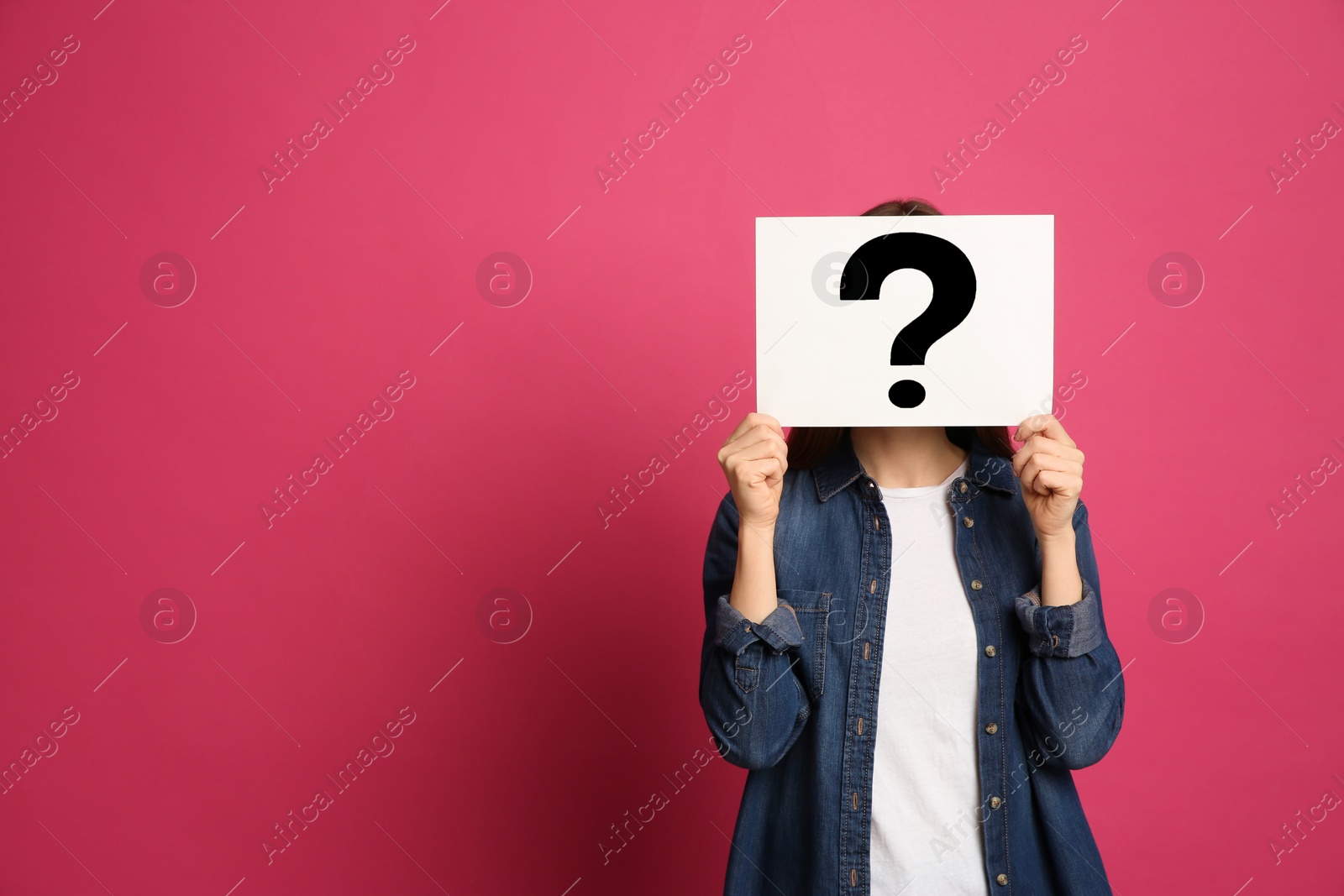 Photo of Woman holding question mark sign on pink background. Space for text