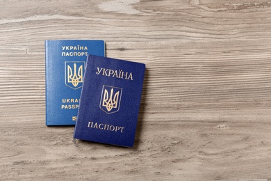 Photo of Ukrainian passports on wooden background, top view with space for text. International relationships