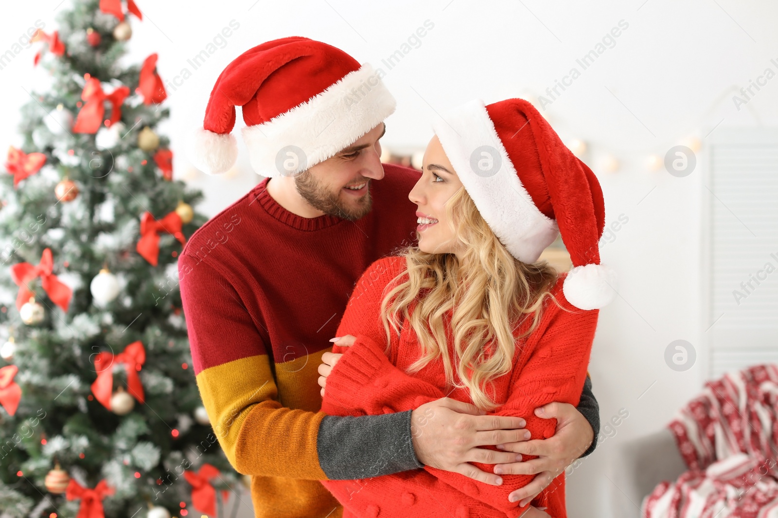 Photo of Young couple in Santa hats at home. Christmas celebration