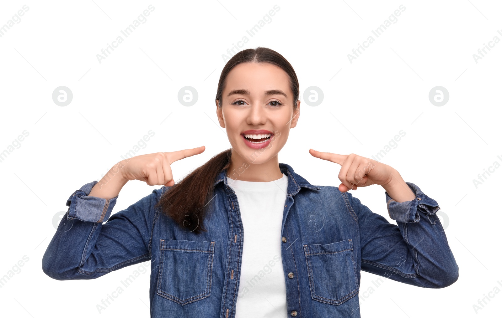 Photo of Young woman pointing at her clean teeth and smiling on white background