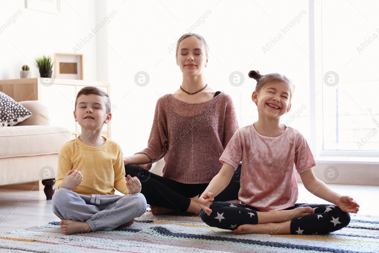 Photo of Young mother and her children practicing yoga at home