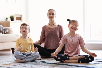 Young mother and her children practicing yoga at home