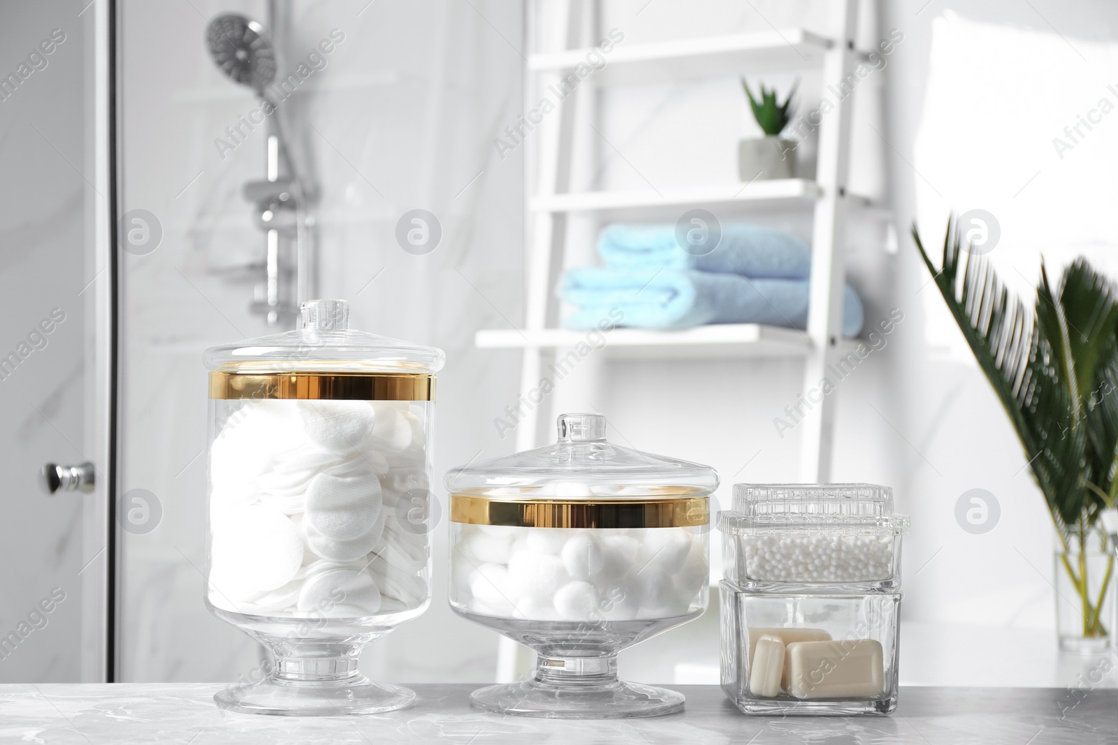 Photo of Cotton balls, swabs, pads and soap bars on light grey marble table in bathroom