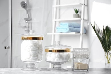 Cotton balls, swabs, pads and soap bars on light grey marble table in bathroom