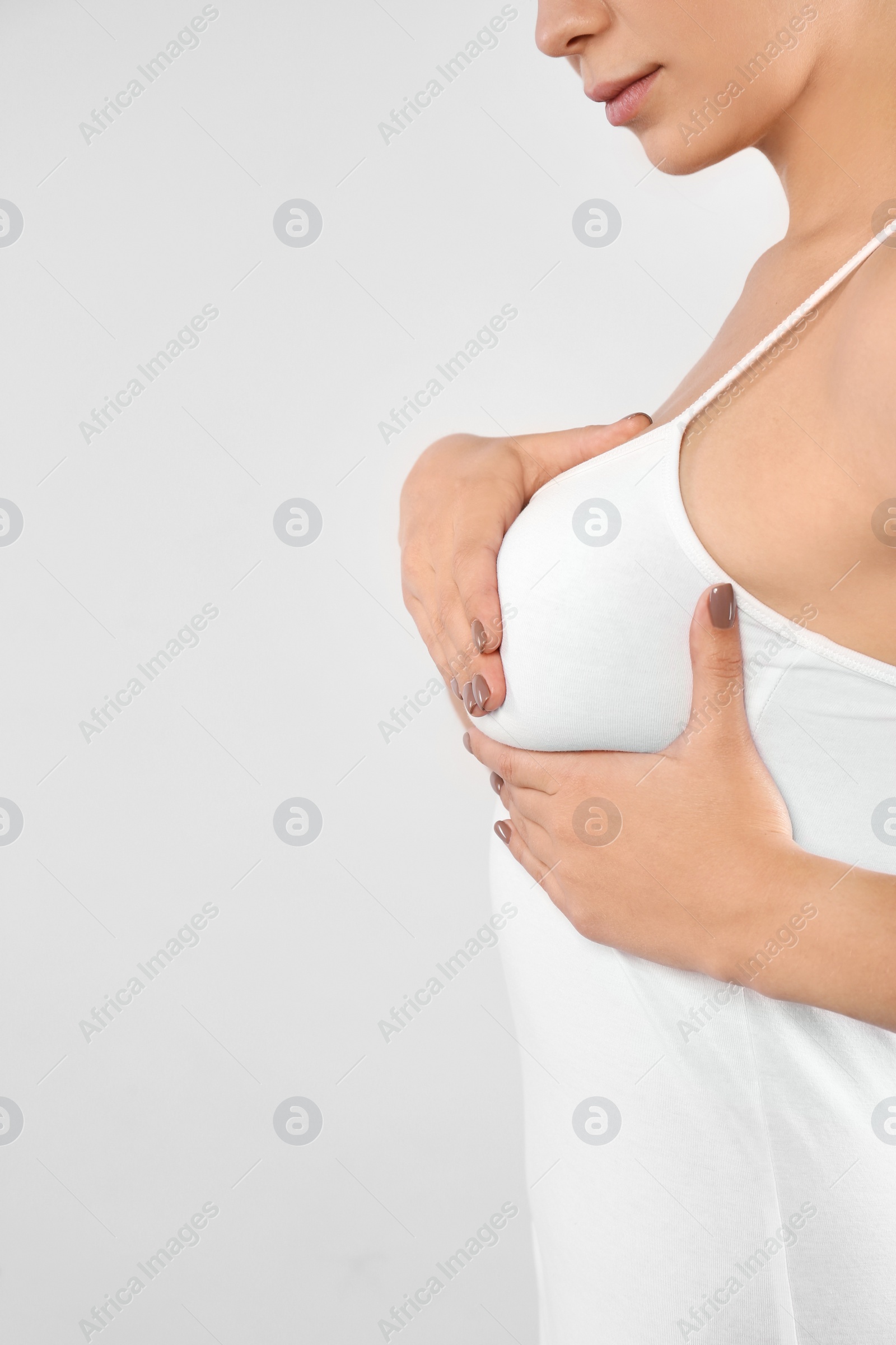 Photo of Woman checking her breast on white background, closeup