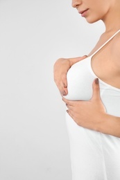 Photo of Woman checking her breast on white background, closeup