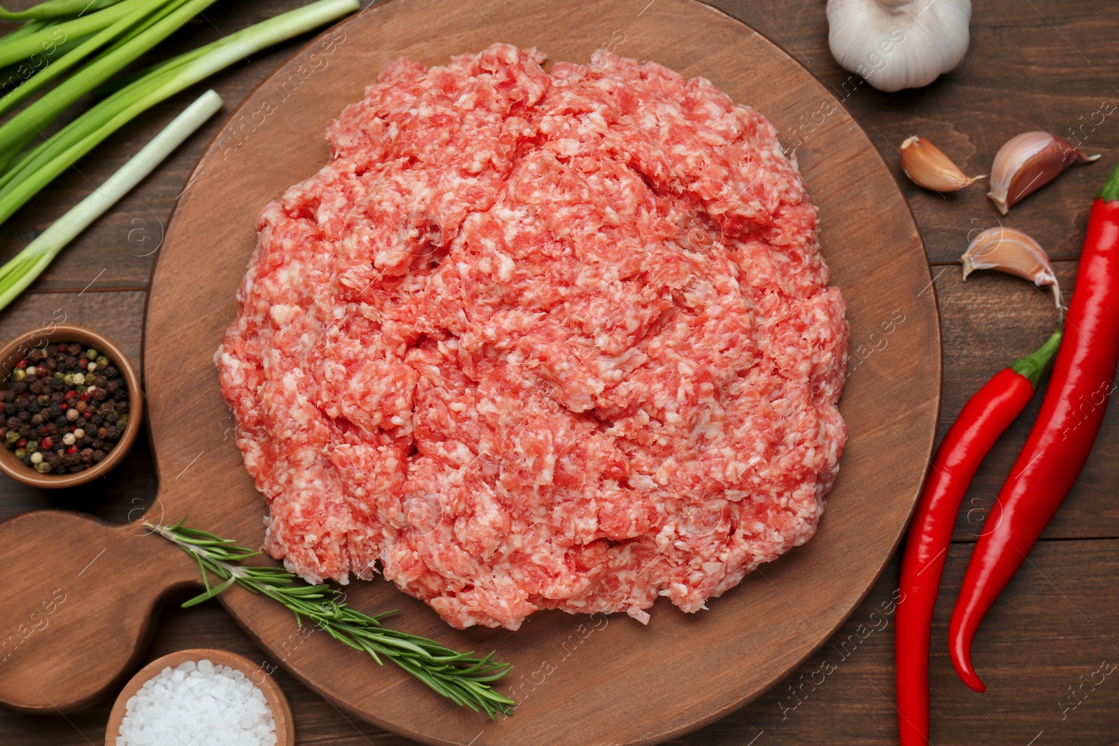 Photo of Raw fresh minced meat and ingredients on wooden table, flat lay