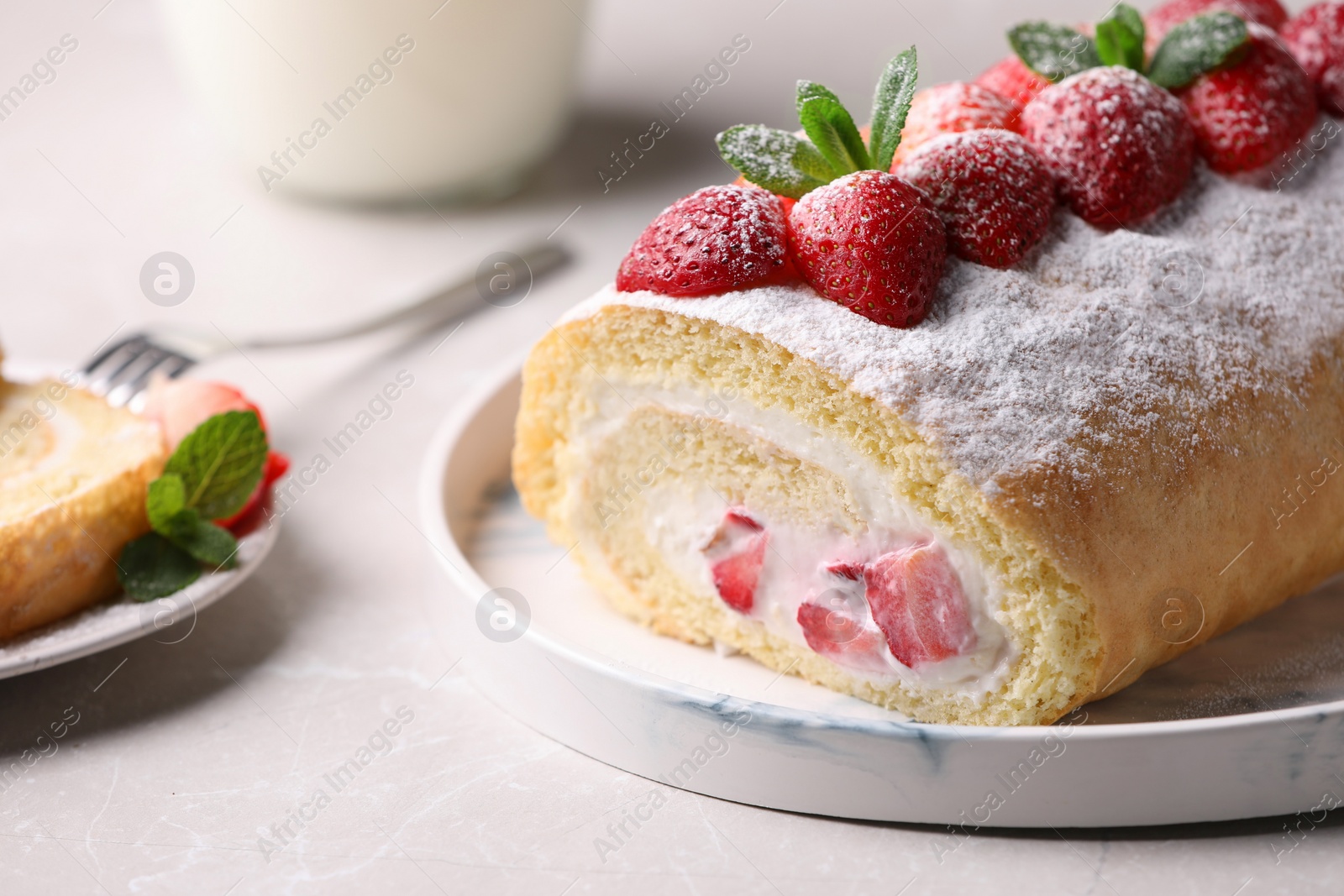 Photo of Delicious cake roll with strawberries and cream on light gray table, closeup