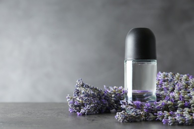 Photo of Deodorant and lavender flowers on grey stone table. Space for text