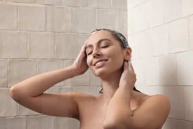 Happy woman washing hair while taking shower at home