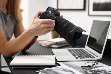 Professional photographer with digital camera at table in office, closeup