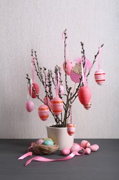 Photo of Beautiful willow branches with painted eggs and Easter decor on light grey wooden table