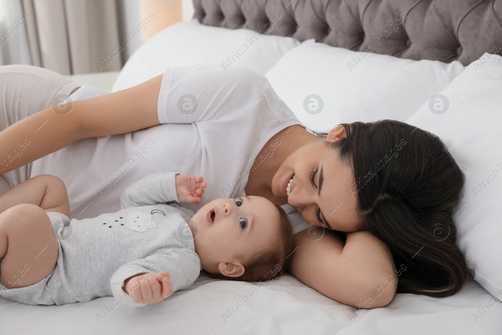 Photo of Portrait of mother with her cute baby lying on bed indoors