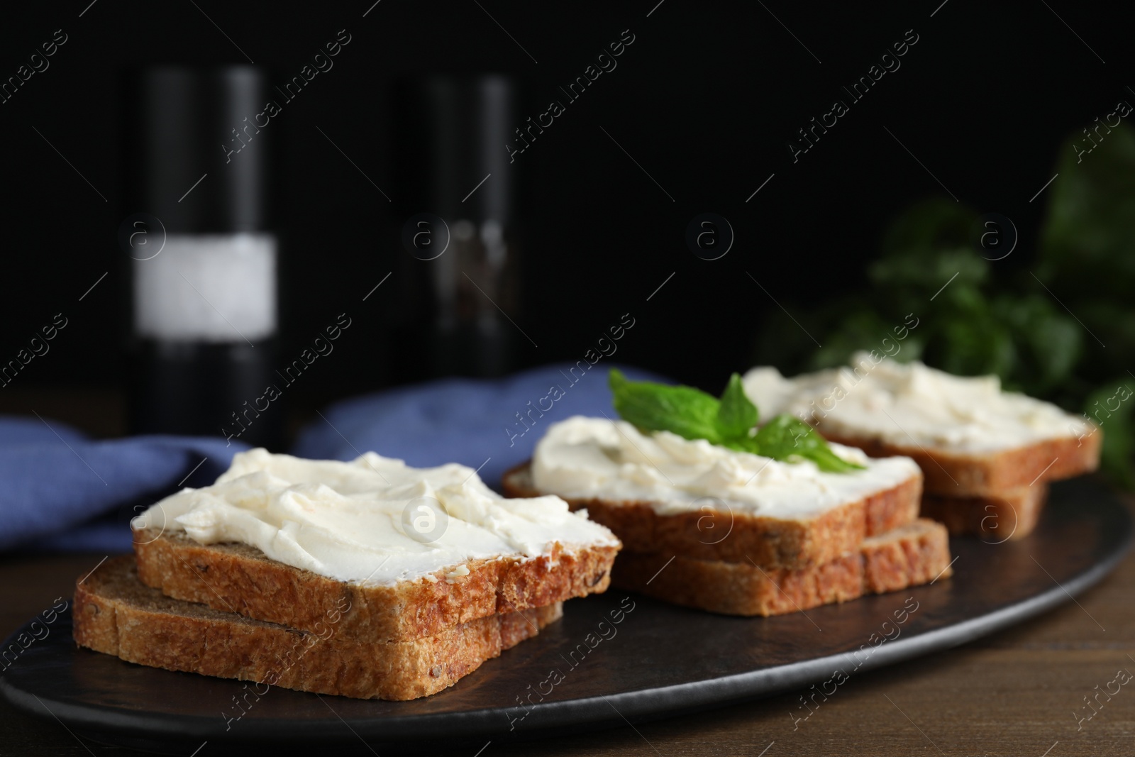 Photo of Bread with cream cheese on wooden table, closeup