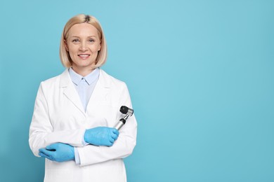 Photo of Happy dermatologist with dermatoscope on light blue background, space for text