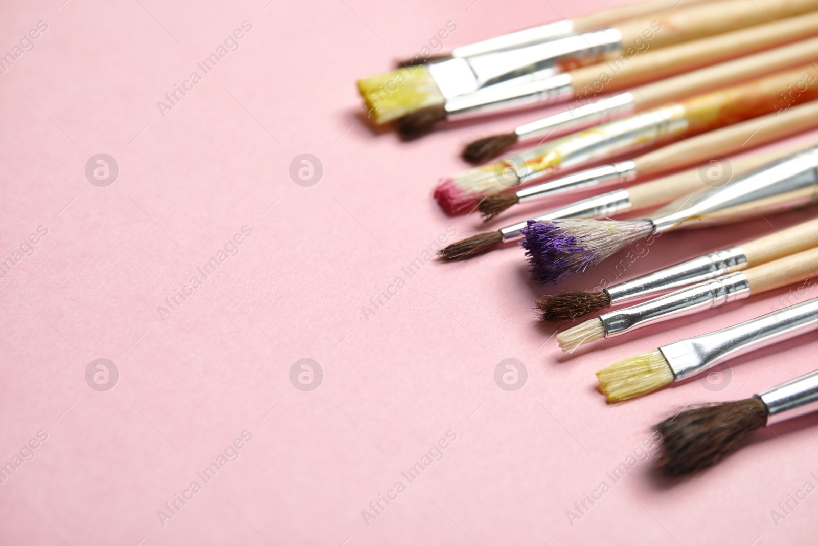 Photo of Different paint brushes on color background. Space for text