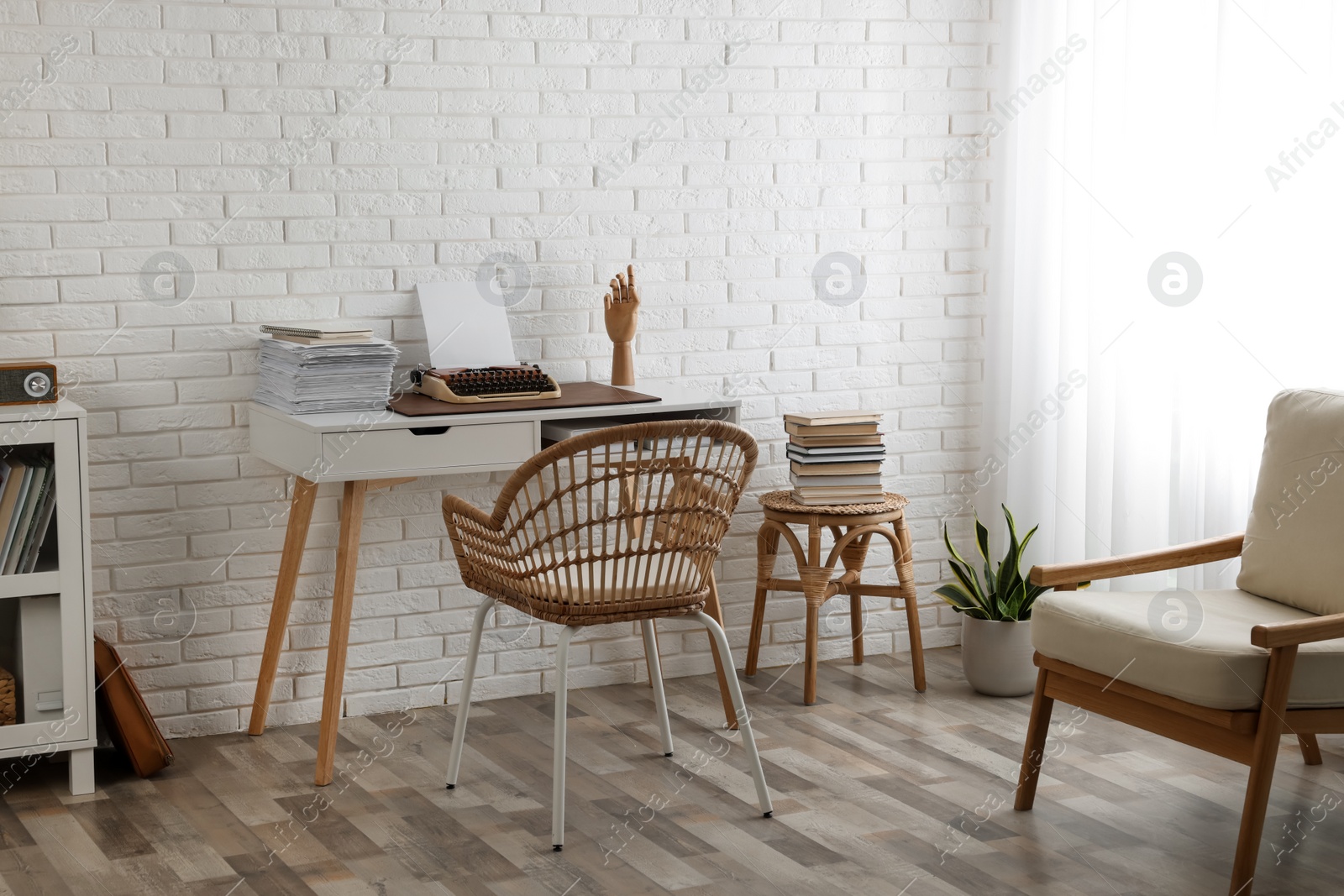 Photo of Comfortable writer's workplace interior with typewriter on desk near white brick wall