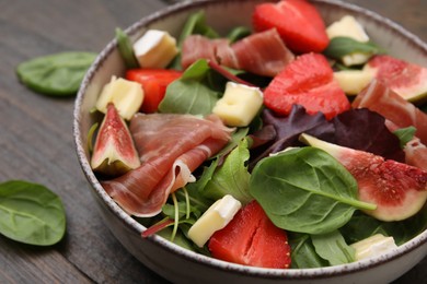 Photo of Tasty salad with brie cheese, prosciutto, strawberries and figs on table, closeup