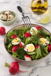 Delicious salad with radish, lettuce and boiled quail eggs served on white marble table, closeup