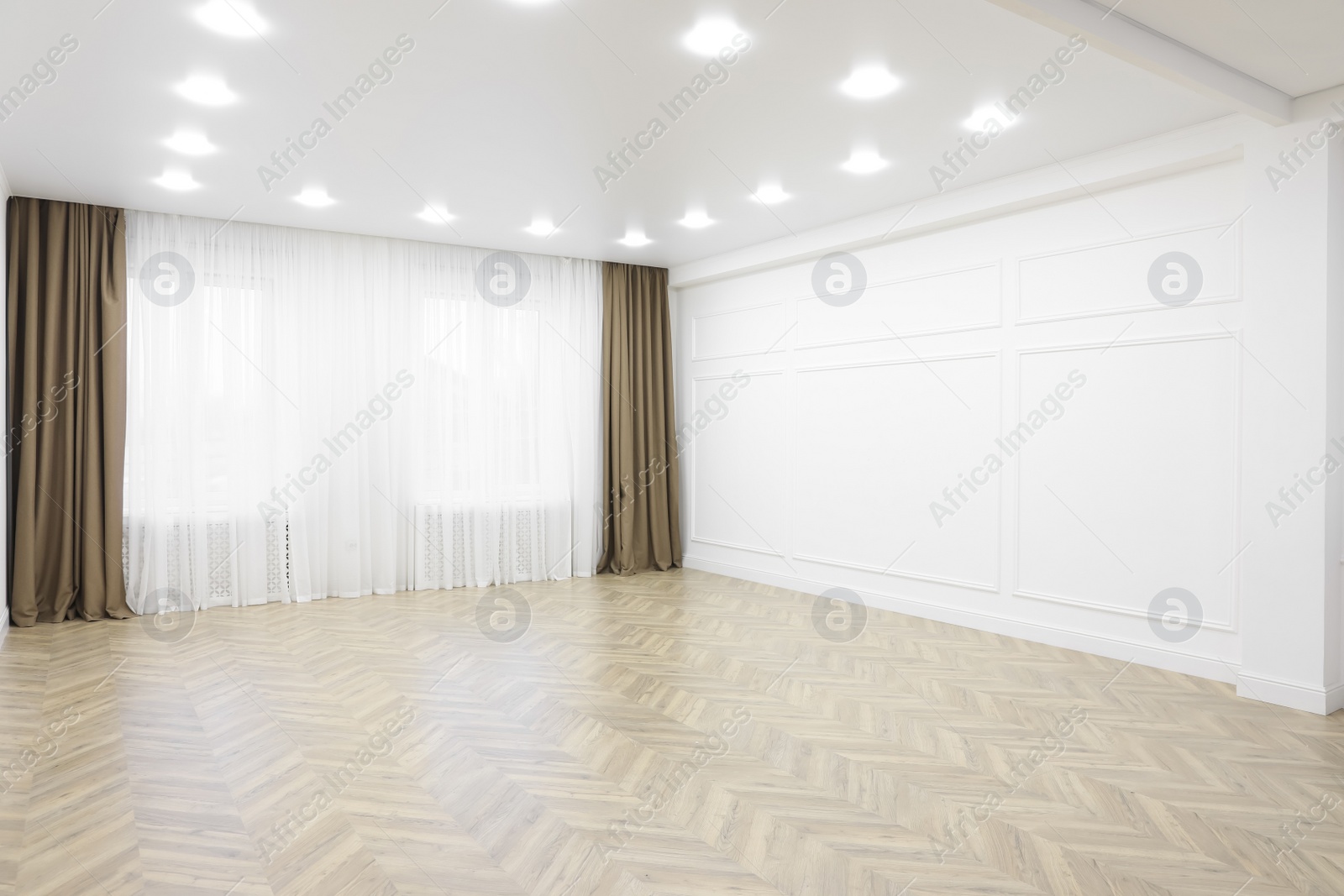 Photo of Empty room with white wall, wooden floor and spot lamps on ceiling