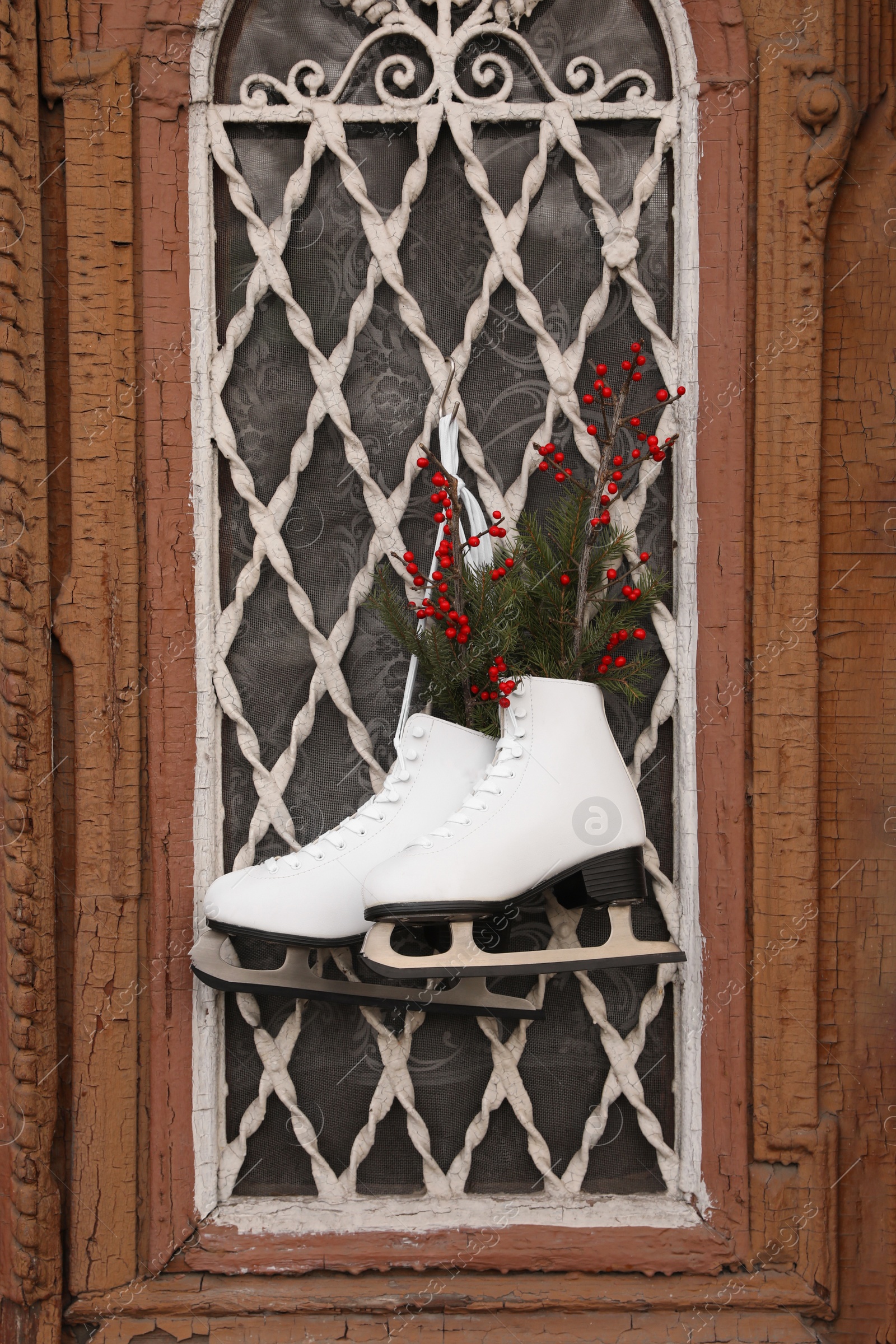 Photo of Pair of ice skates with Christmas decor hanging on old door